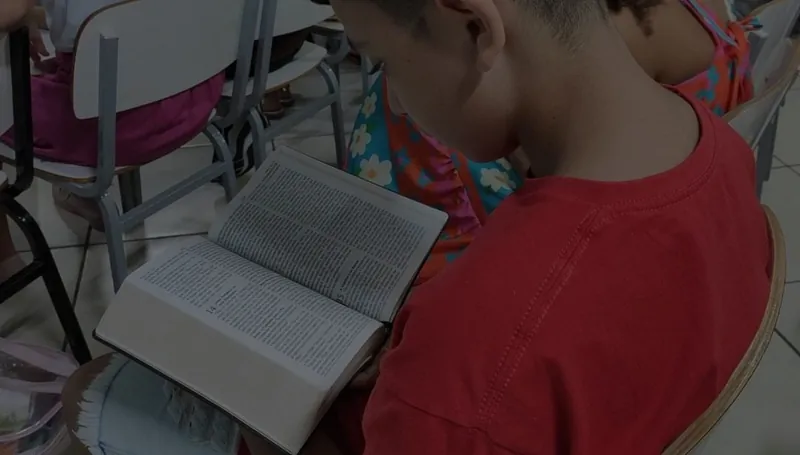 Criança lendo a Bíblia na classe infantil